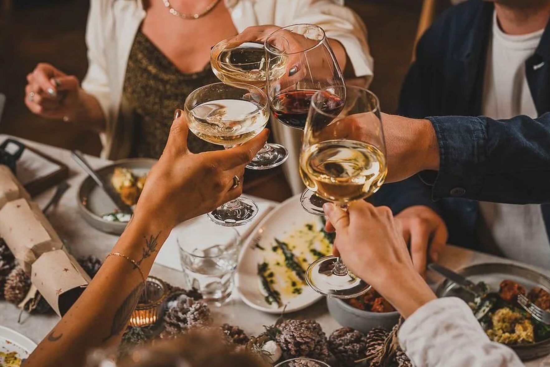 A cheers of glasses of wine around a festive table.